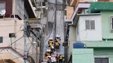Доброволци от Червения кръст на Южна Корея се катерят по стълби в град Бусан, за да доставят помощи на уязвими хора.