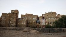 Деца са застанали пред исторически сгради в стария квартал на Сана, Йемен, обхванат от военен конфликт от 2014 г.