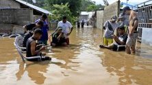 Хора сред наводнена улица в Дили, Източен Тимор. Проливните дъждове потопиха под вода части от столицата.