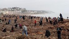 Доброволци почистват брега на Барселона, Испания, след преминаването на бурята Глория, която погуби най-малко 13 души, а 10 все още се издирват.
