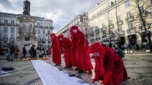 Протестиращи в червени костюми в Лисабон, Португалия, правят лодки от хартия в памет на загиналите мигранти при опит да достигнат Европа по море.