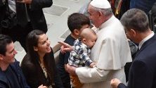 Папа Франциск държи бебе по време на генерална аудиенция във Ватикана.
