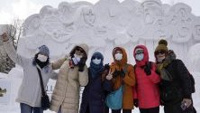 Посетители на снежния фестивал в Сапоро, Япония, позират със защитни маски срещу коронавируса.
