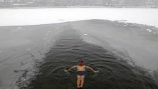 Ентусиаст плува в ледените води на полузамръзналото езеро Хухай в Пекин, Китай.