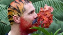 Служител в Кю Гардънс позира до цвете преди откриването на 25-ия Фестивал на орхидеите в Лондон. Над 5000 вида орхидеи участват в проявата, която продължава до 8 март.