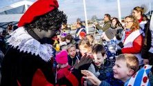 Преоблечен като Черния Пит поздравява деца в село Гру, Холандия. Според легендата Синт Питер е брат на Sinterklaas и идва два месеца след него. Той е винаги придружаван от Черния Пит.