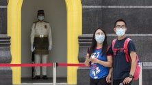 Туристи със защитни маски срещу коронавируса минават край двореца в Куала Лумпур, Малайзия.