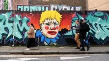 Пешеходци минават край графити, осмиващи британския премиер Борис Джонсън, в Лондон.