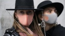Посетители на Седмицата на модата в Лондон носят модни маски за лице срещу коронавируса.
