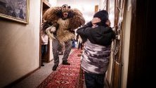 Преоблечен мъж в традиционен костюм плаши гостите в хотел преди да премине по улиците на село Арола, Швейцария, част от карнавала Еволене.
