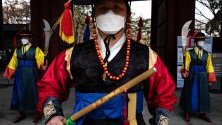 Южнокорейски гвардейци със защитни маски срещу коронавируса изпълняват церемониалните си функции пред двореца в Сеул.