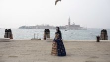 Жена в традиционен костюм за карнавала във Венеция се разхожда из града. Броят на туристите, идващи в града за карнавала, падна значително заради коронавируса.