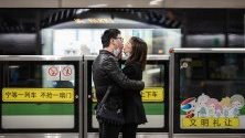 Двойка се целува със свалени маски срещу коронавируса докато чакат влак на гарата в Шанхай, Китай. 