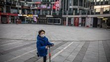 Момченце с предпазна маска срещу коронавируса си играе на празен площад в търговски район в Пекин, Китай.