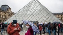 Туристи с предпазни маски чакат пред Лувъра, който е затворил за неопределено време заради коронавируса.