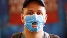 Американец позира със защитна маска, след като гласува на първичните избори на Демократите в секция в Тайланд.