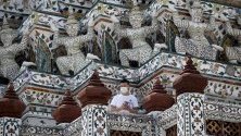 Китайски турист с предпазна маска срещу коронавируса подещава Уат Арун - Храмът на зората, в Банкок, Тайланд. Страната очаква спад на туристите до най-ниското ниво от четири години.