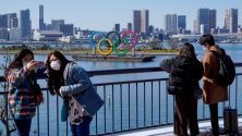 Туристи с предпазни маски позират пред олимпийските пръстени в Токио, Япония. Очаква се Олимпиадата да бъде отложена за края на годината.